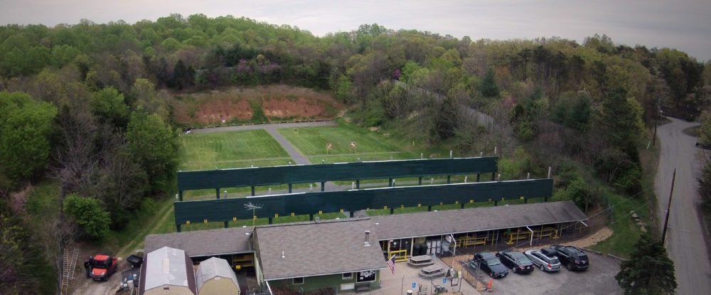 Drone photo looking down the covered firing line at the Rifle & Pistol range, with the berm and target area beyond